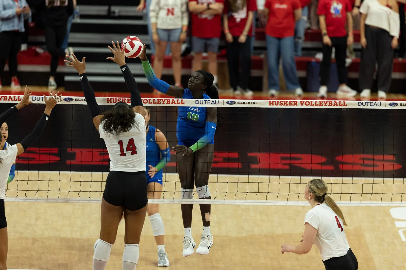 Manaia Ogbechie (14) goes up at the net against an FGCU attacker as Campbell Flynn (4) watches from behind her.