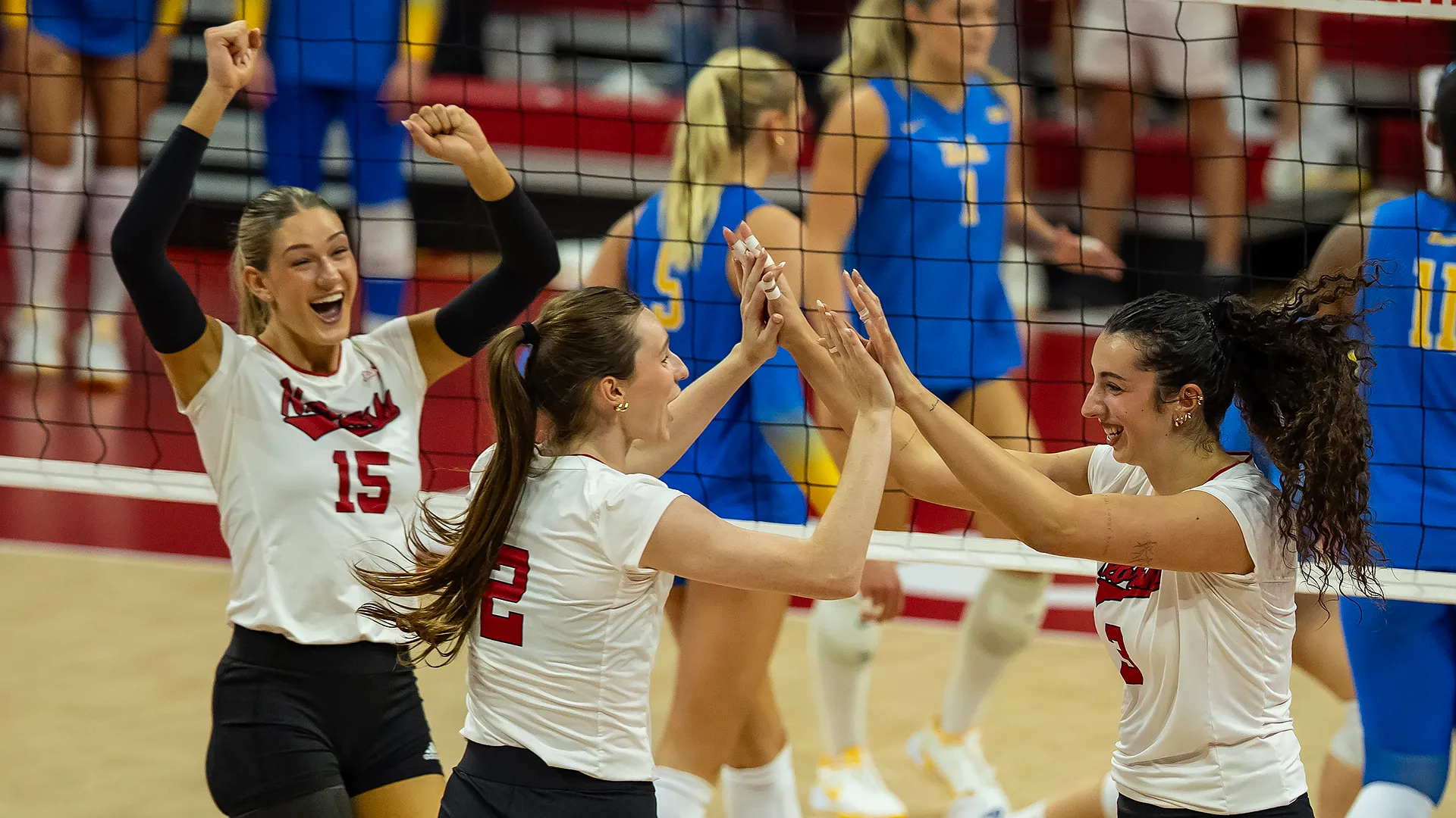 Nebraska's No. 15 Andi Jackson shouts and pumps both fists while No. 2 Bergen Reilly and No. 3 Virginia Adriano high five at the net after a point against UCLA at John Cook Arena.