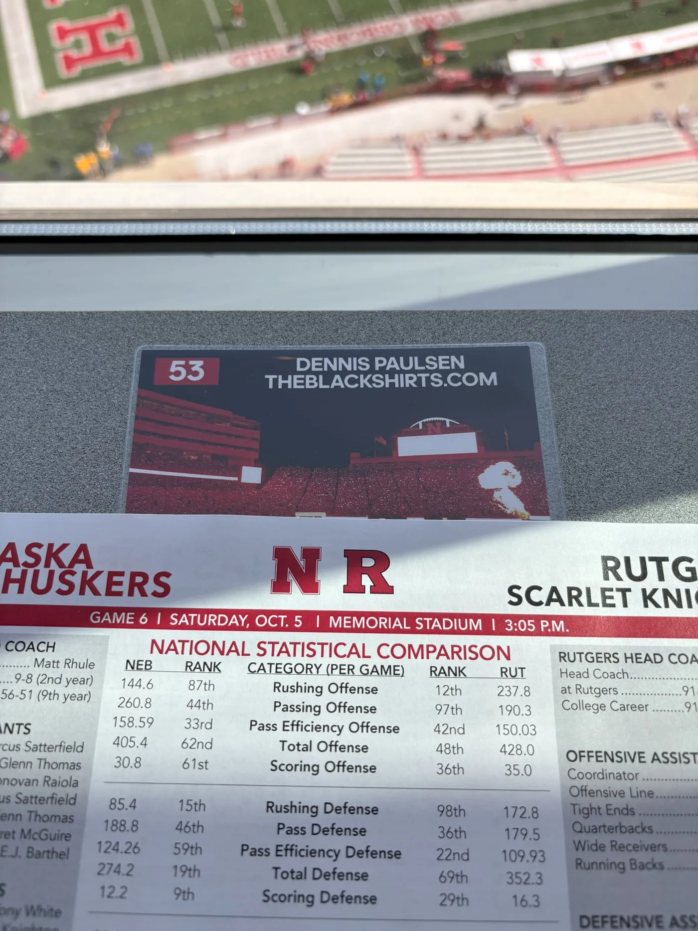A Nebraska press credential reading 53, Dennis Paulsen, theblackshirts.com, resting on the printed Nebraska–Rutgers game notes.